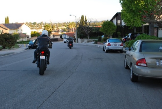Two riders heading away down a suburban California street