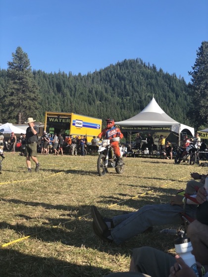 Jonathan riding the 2016 Husqvarna 701 Enduro at the 2018 Touratech Rally with a rally tent and spectators behind