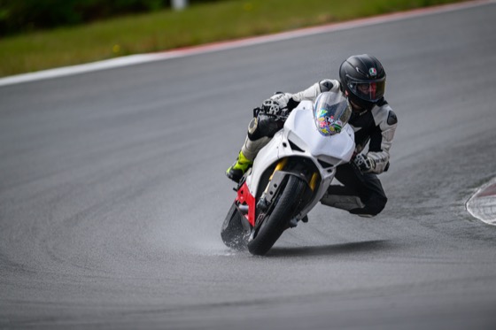 Jonathan carving a wet corner on the white Panigale with spray off the tires