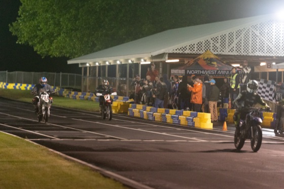 Riders crossing the line under the checkered flag at midnight (photo 75 of 77)