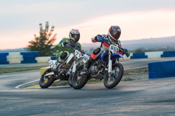 John Gessner on the #711 alongside a blue bike through a corner at sunset (photo 53 of 117)