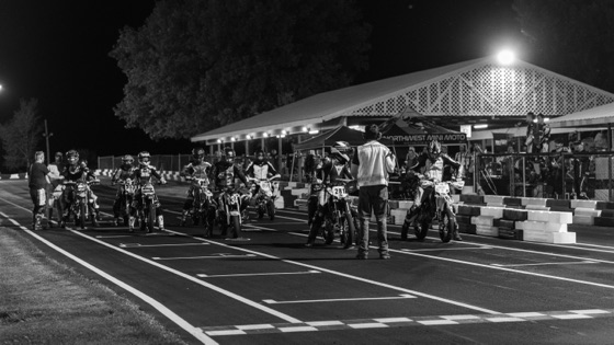 Black and white: riders lined up on the grid for a night restart under the lights (photo 68 of 117)