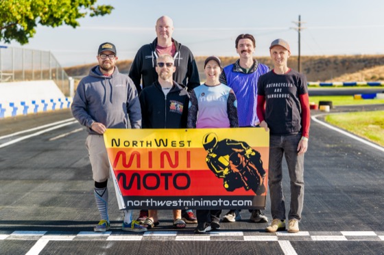 The Spiva Racing Team holding a NorthWest Mini Moto banner at the start finish line
