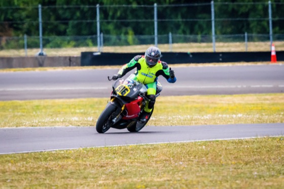 Jonathan Spiva sitting up with a hand raised on the #916 Panigale R at Portland International Raceway