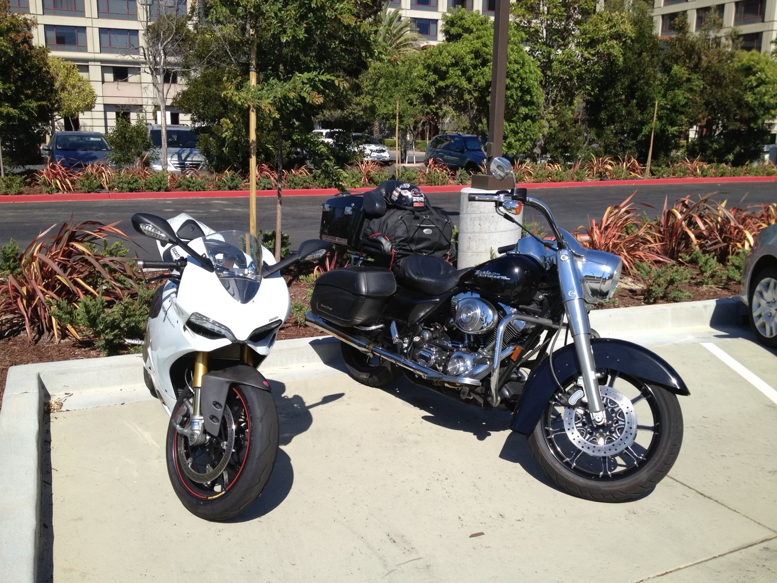 A white 2013 Ducati 1199 S parked next to a loaded Harley-Davidson bagger in a parking lot