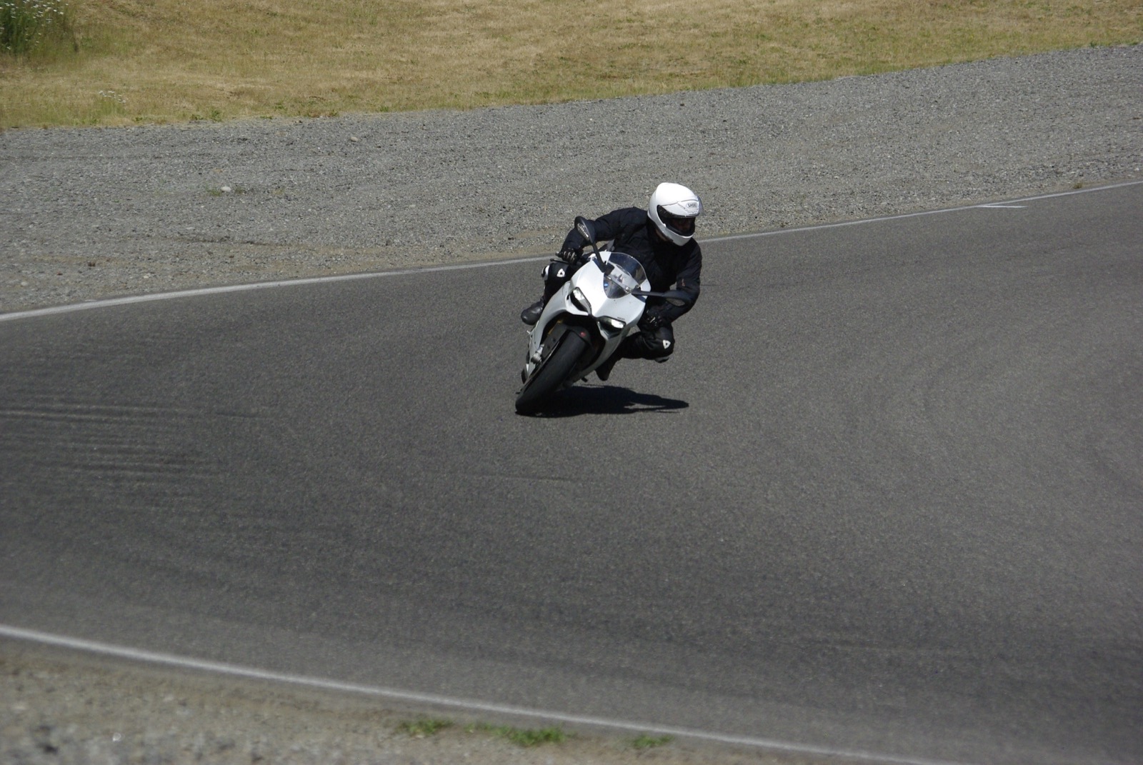 Jonathan cornering a white 2013 Ducati 1199 S on track in black leathers