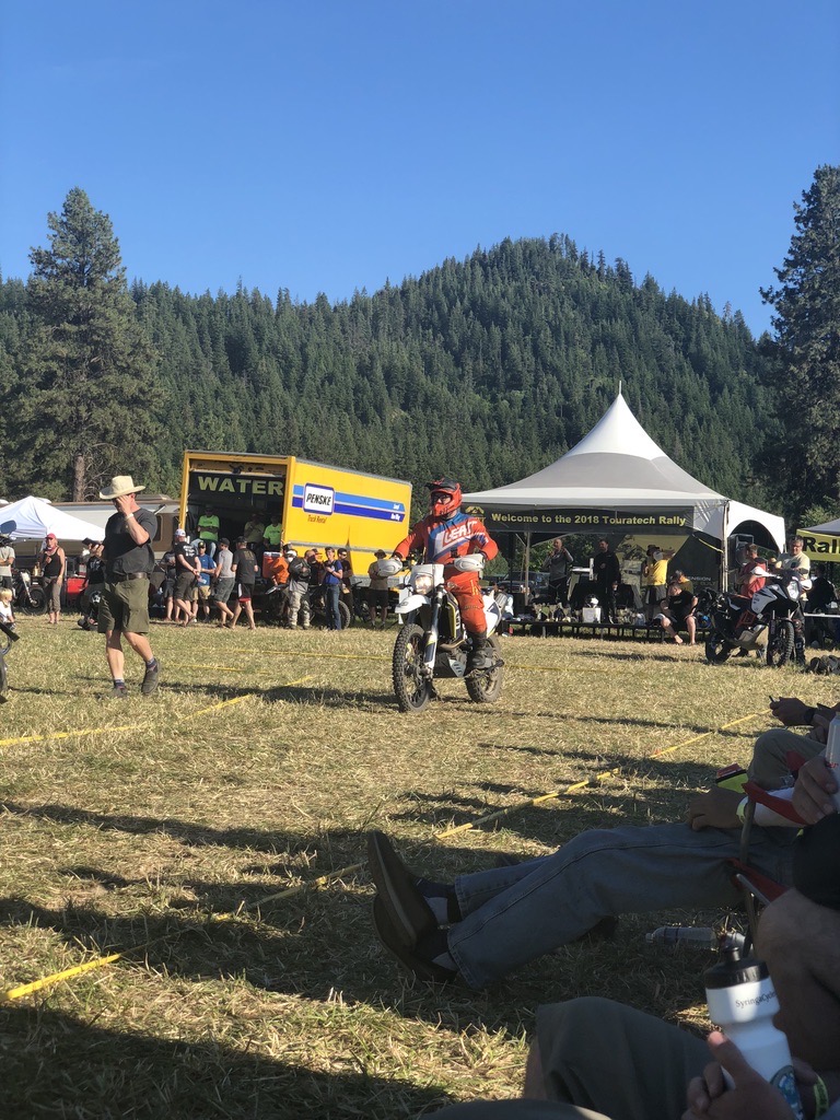 Jonathan riding the 2016 Husqvarna 701 Enduro at the 2018 Touratech Rally with a rally tent and spectators behind