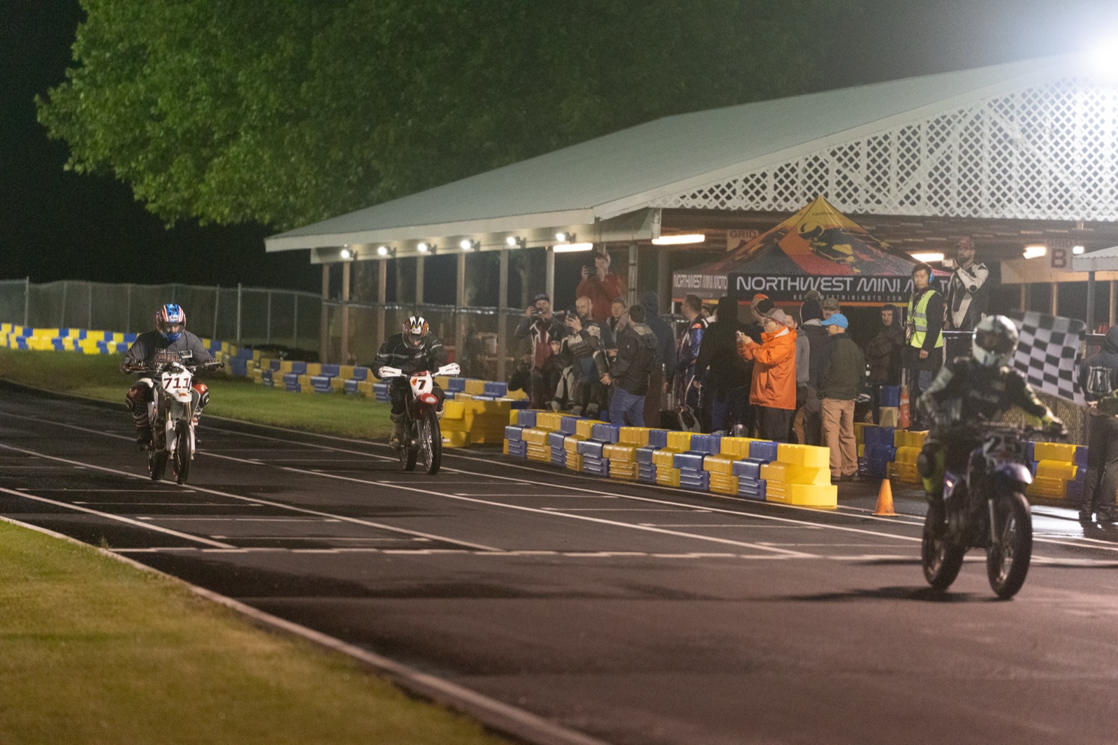 Riders crossing the line under the checkered flag at midnight (photo 75 of 77)