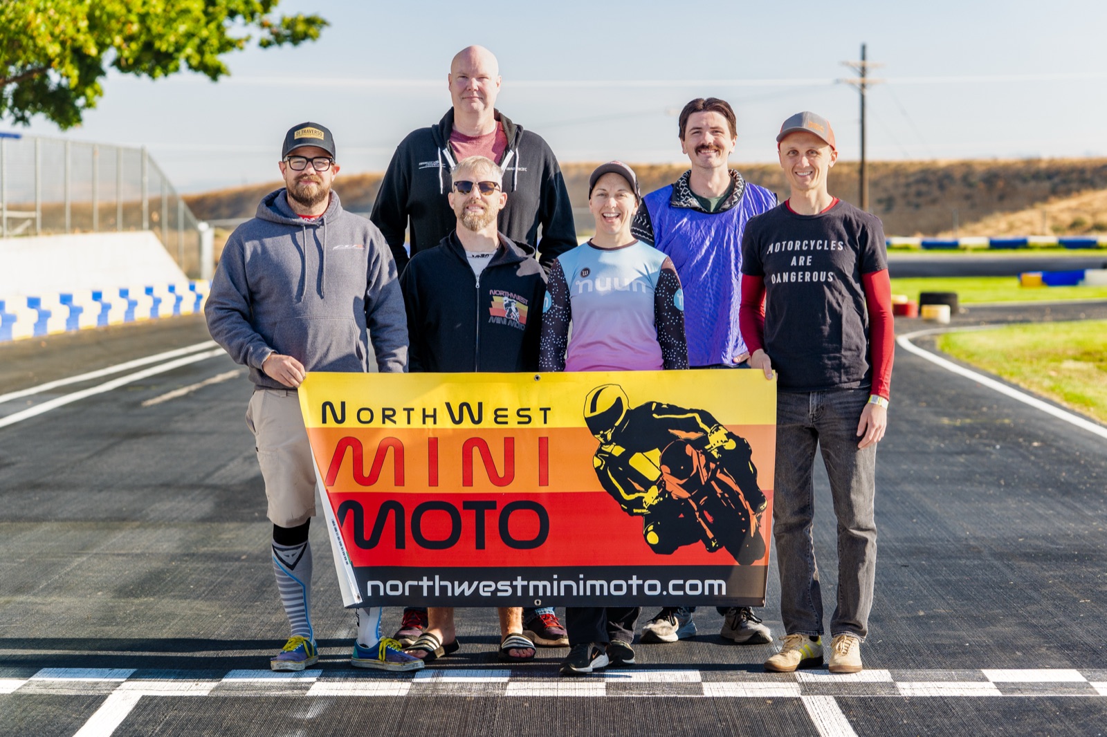 Jonathan Spiva, Garrick Fulbright, Gavin Soderholm, Hannah Johnson, John Gessner and Alex Taylor holding a NorthWest Mini Moto banner at the start finish line (photo 2 of 117)