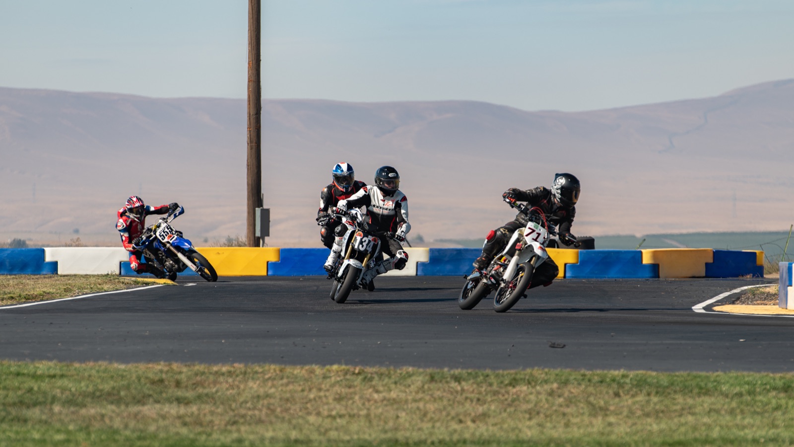 Riders spread through a corner with the hills behind (photo 20 of 117)