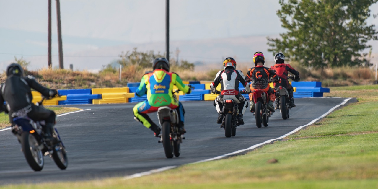A pack of minimoto riders through a corner at Tri City Kart Club