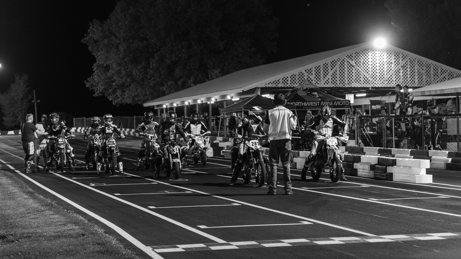 Black and white: riders lined up on the grid for a night restart under the lights (photo 68 of 117)